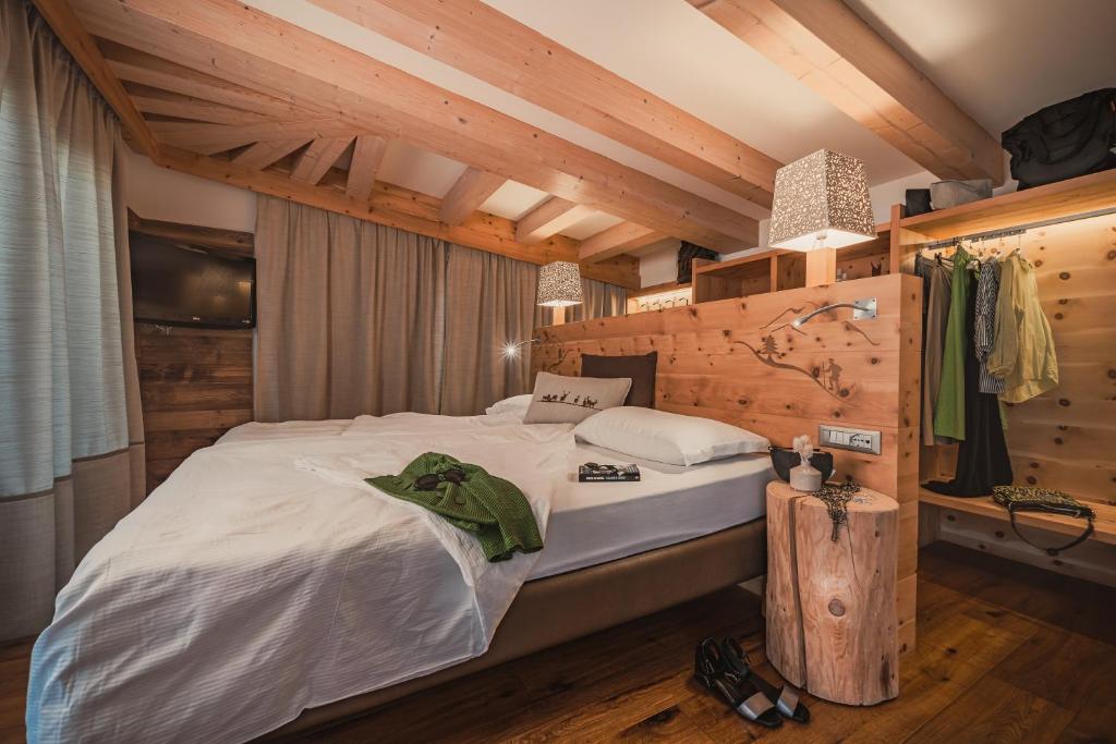 Moderns guļamistabas interjers ar koka sijām un mājīgu gultu, kas papildināta ar stilīgām lampām un drēbju glabāšanu. Svaiga un relaksējoša atmosfēra.