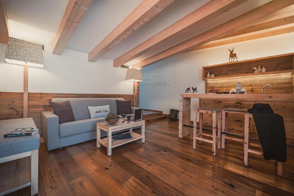 Mūsdienīgs un elegants istabas iekārtojums ar koka sijām un siltām krāsām, kas rada mājīgu atmosfēru. Interjerā ir dīvāns, koka galds un virtuve ar minimālisma elementiem.