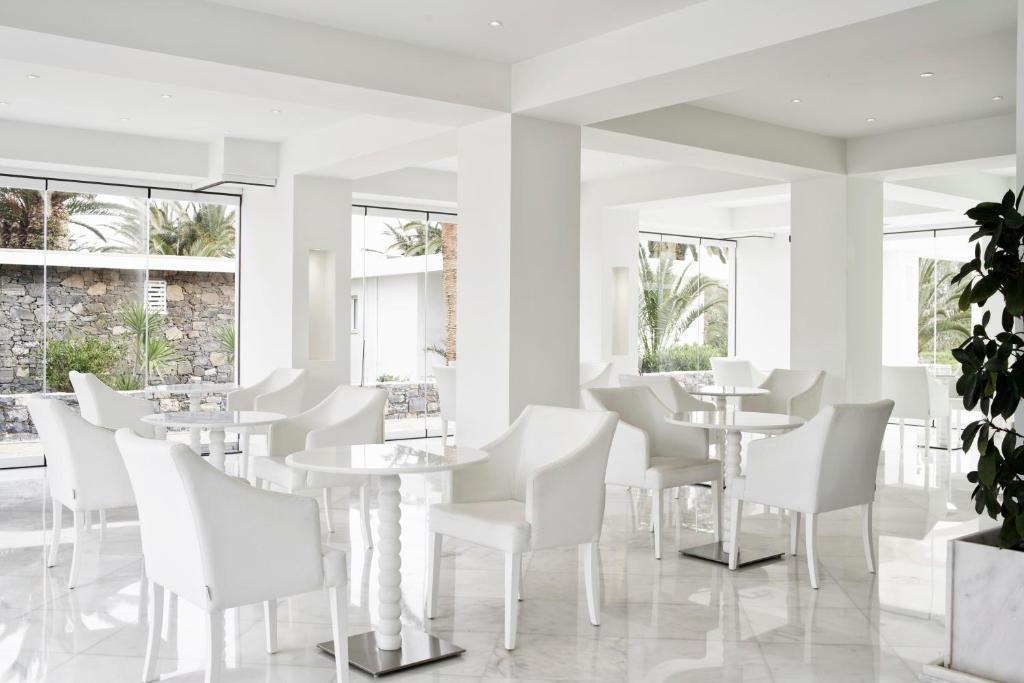 Moderns un elegants kafejnīcas interjers ar baltām mēbelēm un lieliem logiem, kas ļauj iekļūt dabiskajai gaismai. Šī telpa ir paredzēta relaksācijai un patīkamai atpūtai.