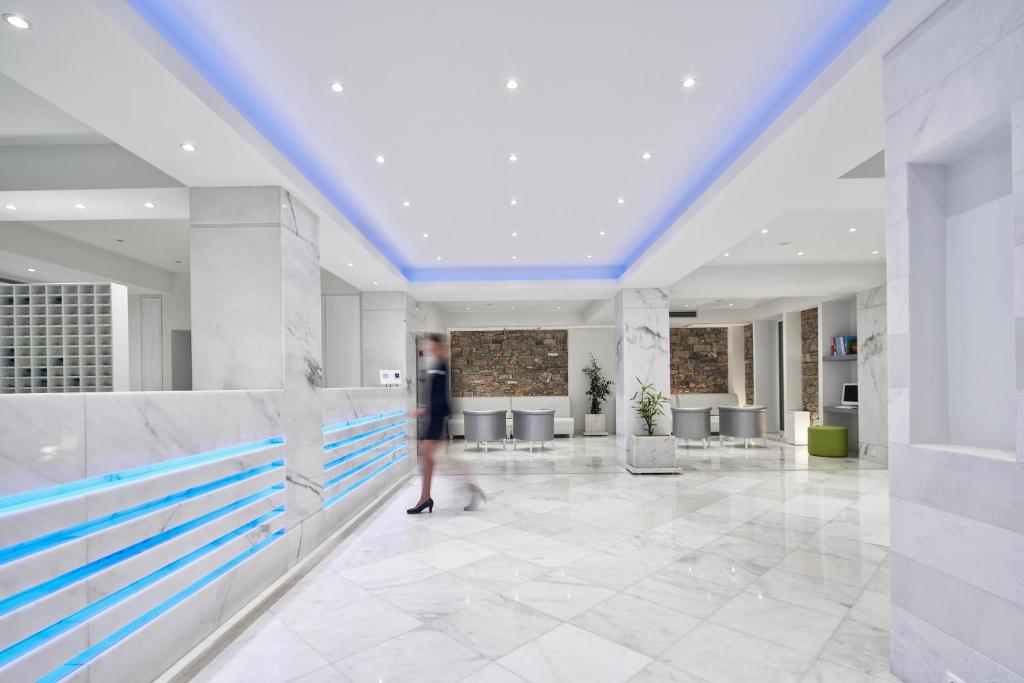 Mūsdienīgs viesnīcas reģistratūras interjers ar marmora grīdu un akmens akcentiem, apgaismots ar mīkstu zilu gaismu.