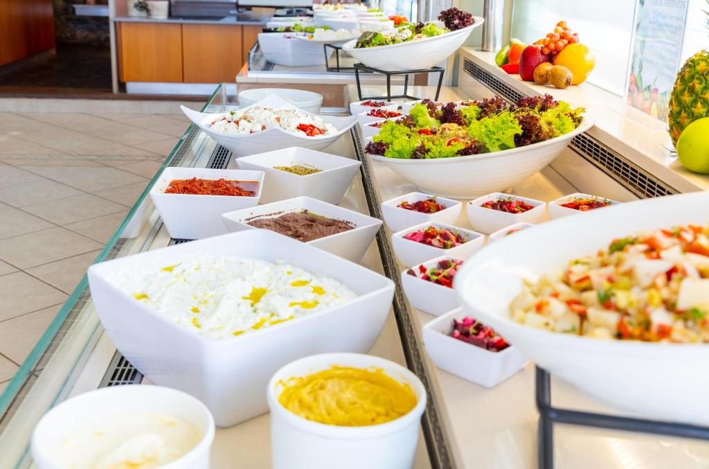 Svaigu salātu un mērču bufete ar dažādām sastāvdaļām, tostarp dārzeņiem, mērču un salātu bļodām. Svaigi augļi un dārzeņi rotā galdu.