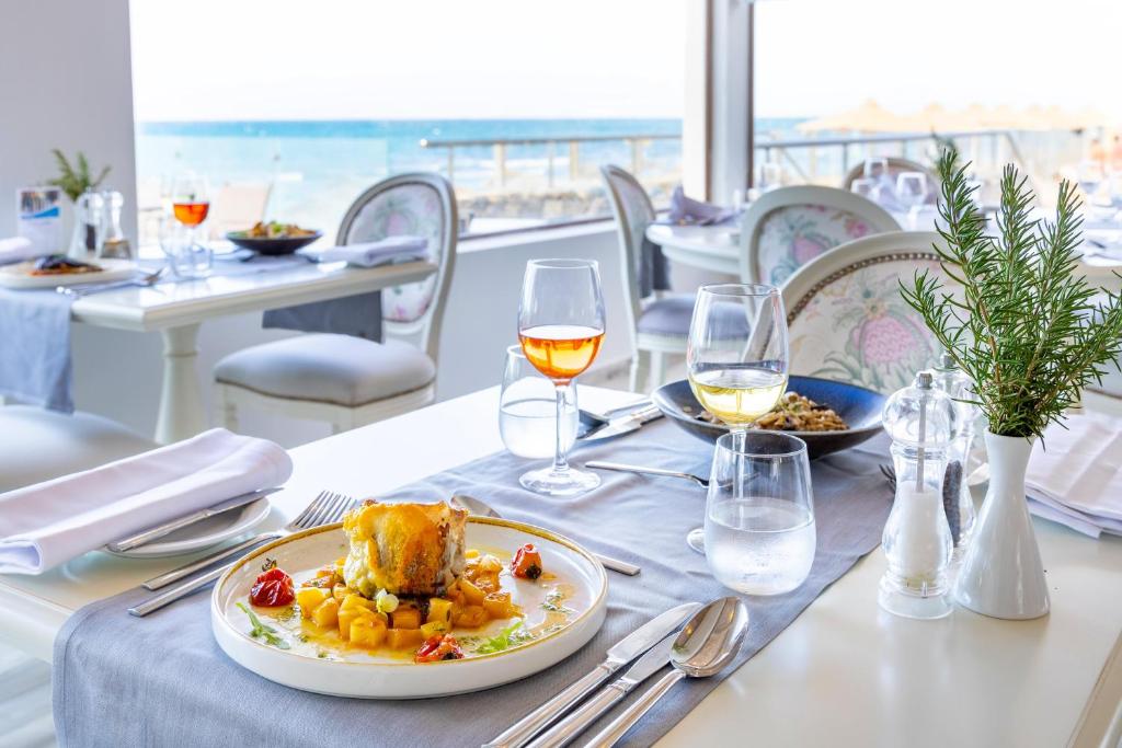 Eleganta restorāna galda izkārtojums pie jūras ar gourmet ēdienu, vīnu un rosmarīnu. Ideāla atmosfēra relaksējošai maltītei pie ūdens.