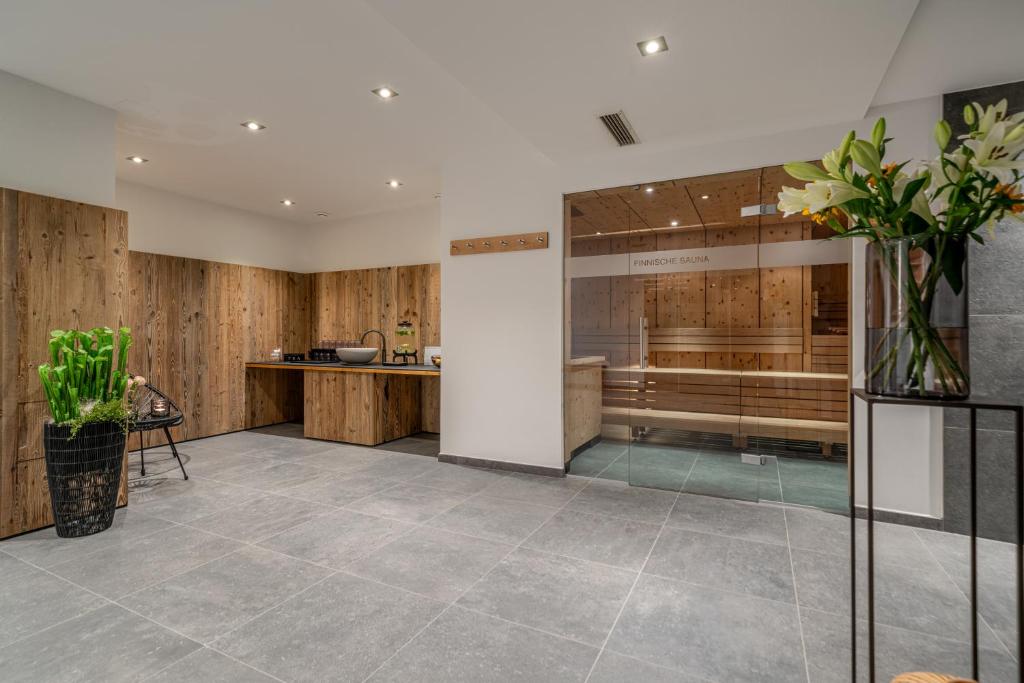 Mūsdienīgs spa interjers ar koka akcentiem, kurā redzama sauna un relaksācijas zona. Telpa ir gaiša un eleganta, ar augiem un komfortablu mēbelējumu.