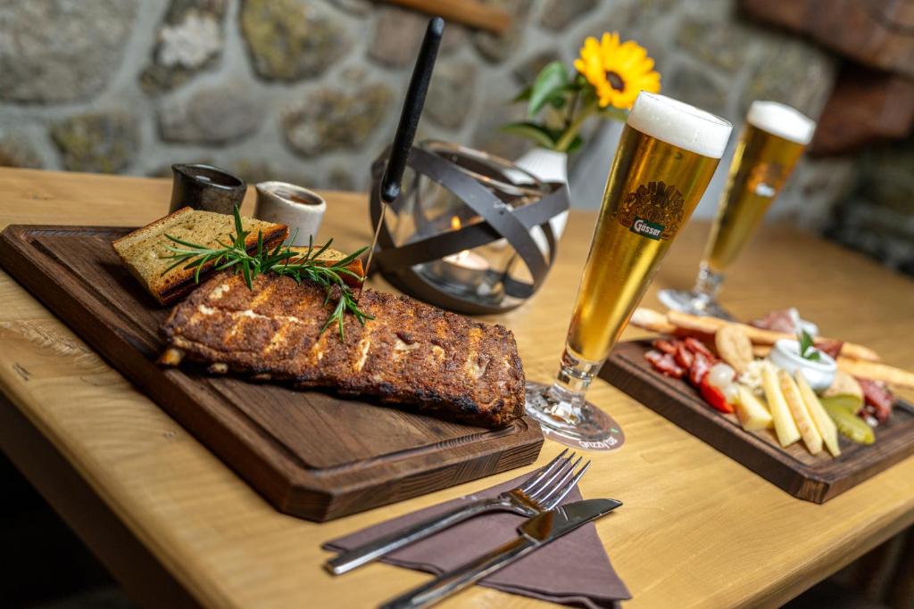 Sātīgas vakariņas ar ceptiem ribām, maizi un dažādām uzkodām, pasniegtas kopā ar divām glāzēm gaisīgas alus. Galda dekors ietver ziedu un siltu gaismu.