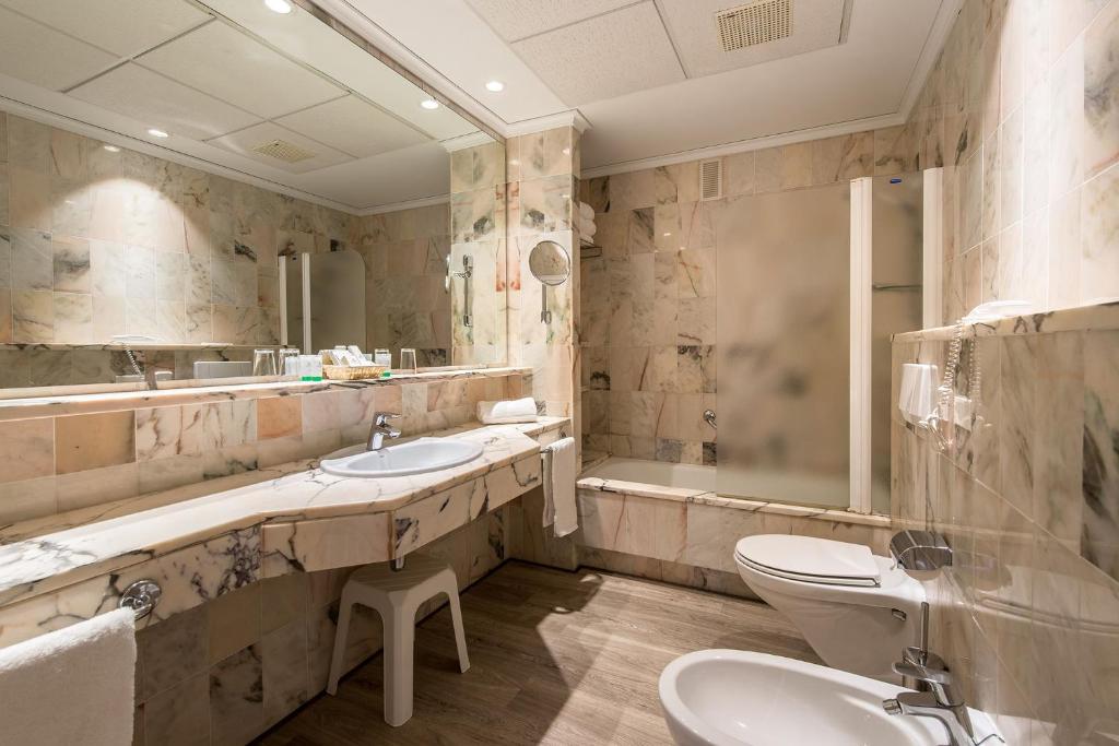 Mūsdienīgs vannas istabas interjers ar marmora apdari, izsmalcinātu izskatu un funkcionalitāti. Telpā redzams izlietne, vanna un dušas kabīne.