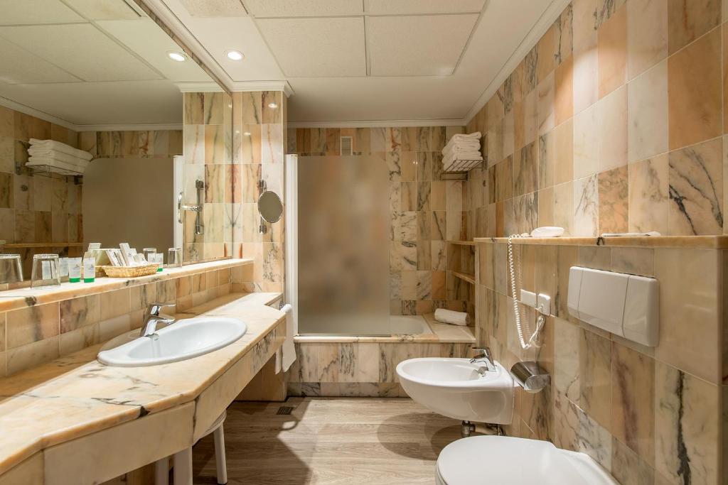 Mūsdienīgs vannas istabas interjers ar marmora apdari, iekļaujot dušu, izlietni un citas nepieciešamās ērtības. Vannas istaba ir gaiša un eleganta, radot relaksējošu atmosfēru.