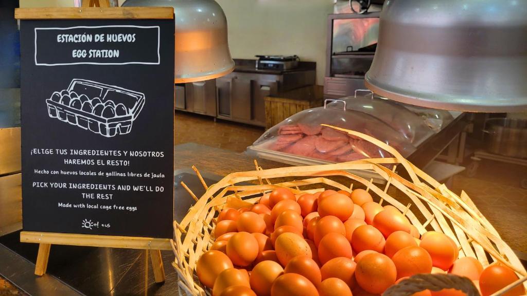 Olu stacija ar informācijas tāfeli par vietējiem olu izvēli un sagatavošanu, ar grozu, kurā atrodas svaigas olas.