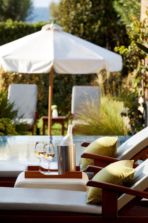 Peldbaseina tuvumā novietots galdiņš ar divām glāzēm vīna un ledus spaini, fonā redzama sauļošanās zona un saulessargs. Ideāla atmosfēra relaksācijai un atpūtai.