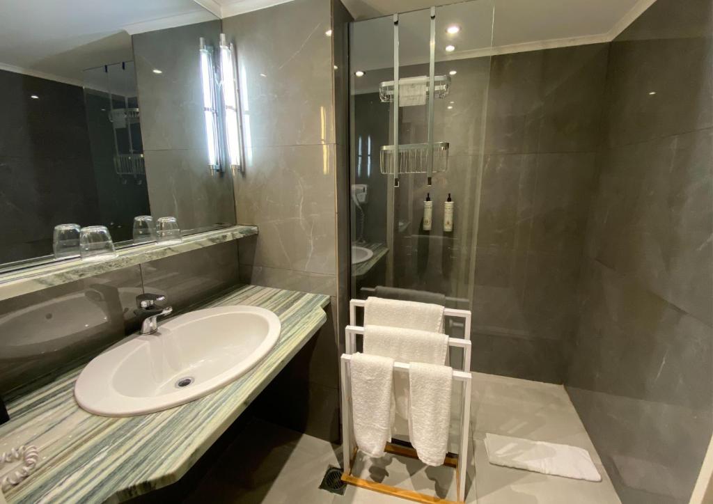 Moderns vannas istabas interjers ar elegantu marmora izlietni un stikla dušu. Gaismas elementi rada patīkamu atmosfēru.