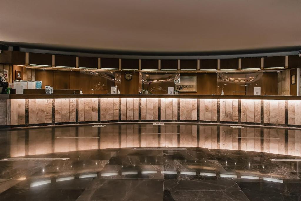 Mūsdienīga viesnīcas reģistratūra ar elegantu apgaismojumu un marmora virsmām. Interjers ir stilīgs un aicinošs, radot patīkamu atmosfēru viesiem.