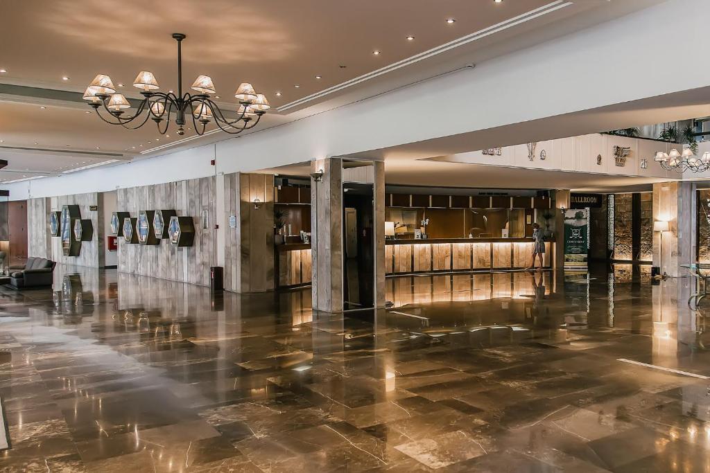 Luksusa viesnīcas reģistratūra ar mūsdienīgu interjeru, elegantām lampām un spīdīgu grīdu. Redzamas pieņemšanas zonas un dekoratīvas mākslas gleznas uz sienām.