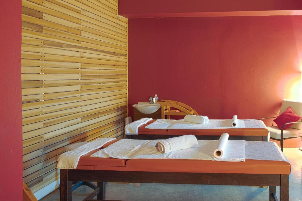 Spa telpa ar masāžas galdiem un siltu interjeru. Sienas ir krāsotas sarkanā tonī, un ir redzams koka apdare.