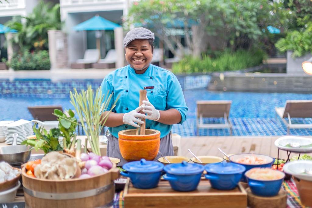 Pavārs ar smaidu pie Grand Mercure Phuket Patong, gatavojot tradicionālos ēdienus.