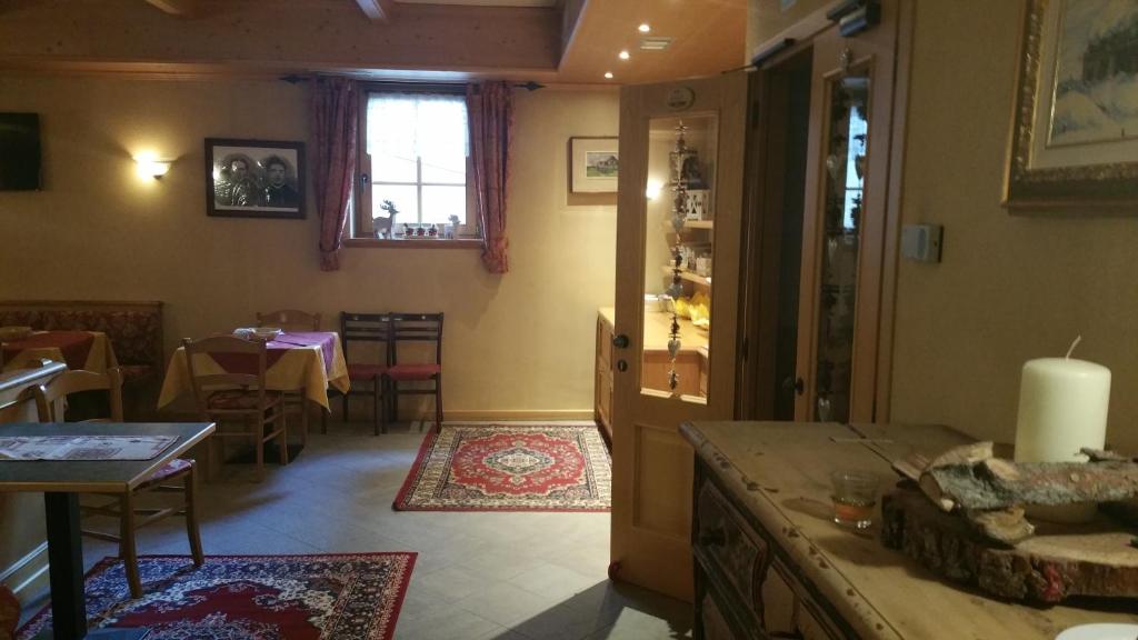 Restorāna interjers ar koka apdari, ēdamgaldiem un tradicionāliem dekoriem, radot siltu un viesmīlīgu atmosfēru. Gaisma ienāk caur logu, papildinot telpas komfortu.