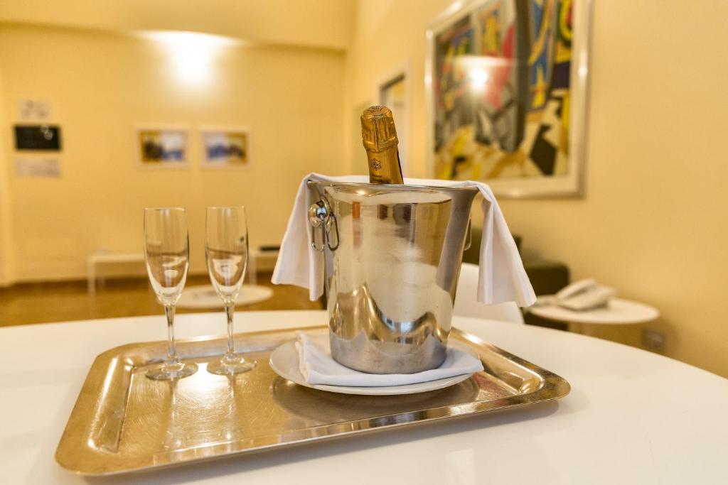 Šampanieša pudele ledus traukā kopā ar divām glāzēm uz sudraba paplātes, modernā interjerā.