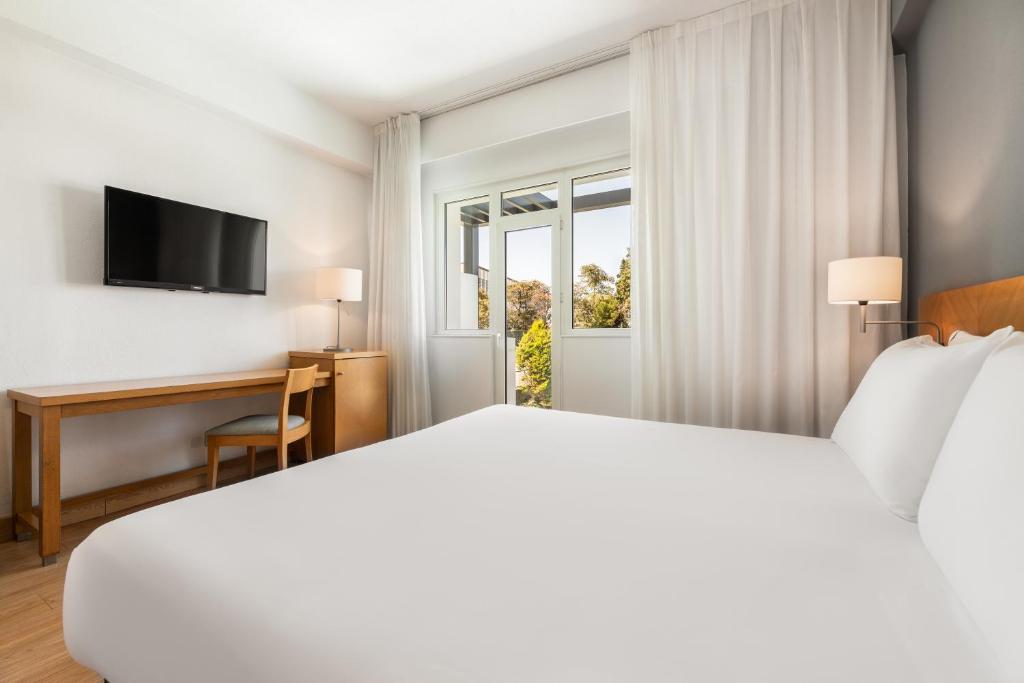 Mūsdienīgs viesnīcas numurs ar plašu gultu, koka galdu un televizoru, kas nodrošina komfortu un gaismu. Logi ar aizkariem ļauj ieplūst dabīgai gaismai un piedāvā skatu uz ārpusi.