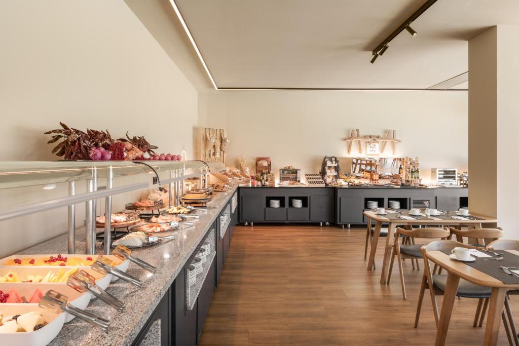 Bufete ar dažādām delikatesēm, kas izkārtotas uz galda, un ēdināšanas zona ar koka mēbelēm.