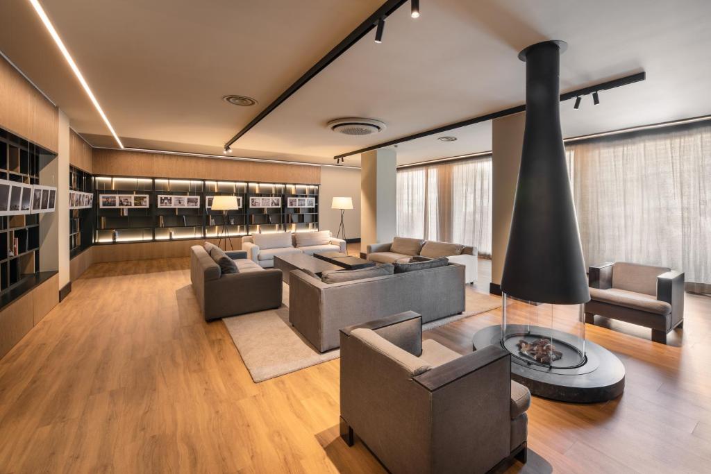 Mūsdienīgs viesnīcas viesistabas interjers ar pelēkiem dīvāniem un kamīnu, kas nodrošina siltumu un komfortu. Gaismas un koka grīdas elementi rada patīkamu atmosfēru.