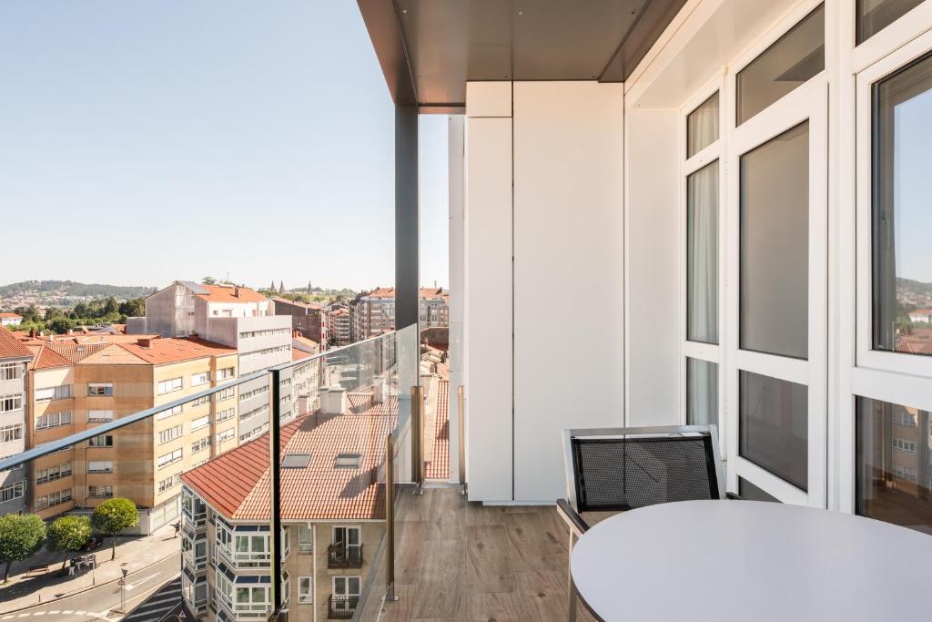 Mūsdienīga balkona terase ar skatu uz pilsētu, kurā redzami daudzstāvu nami un zaļās zonas. Ideāla vieta relaksācijai un pilsētas ainavas baudīšanai.