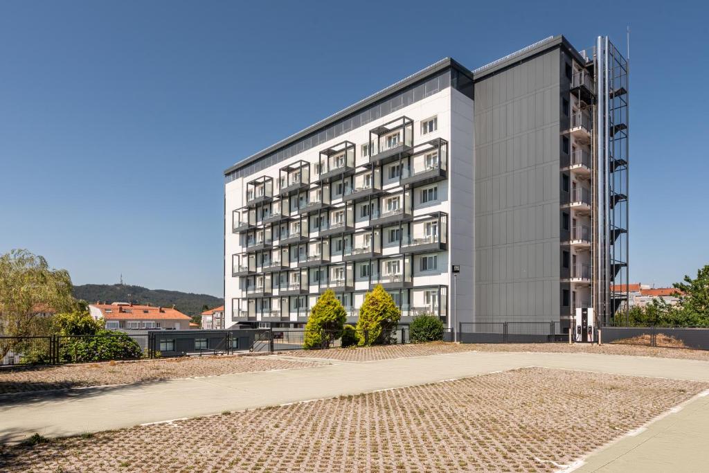 Moderns daudzstāvu nams ar lieliem logiem un balto fasādi, apkārt esošā teritorija ir sakopta un zaļa. Skatā redzams arī kalns fona daļā.