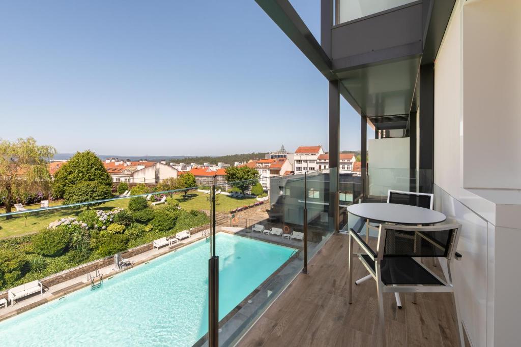 Balkons ar skatu uz peldbaseinu un apkārtējo ainavu, kur redzamas mājas un dārzi. Ideāla vieta atpūtai un relaksācijai.