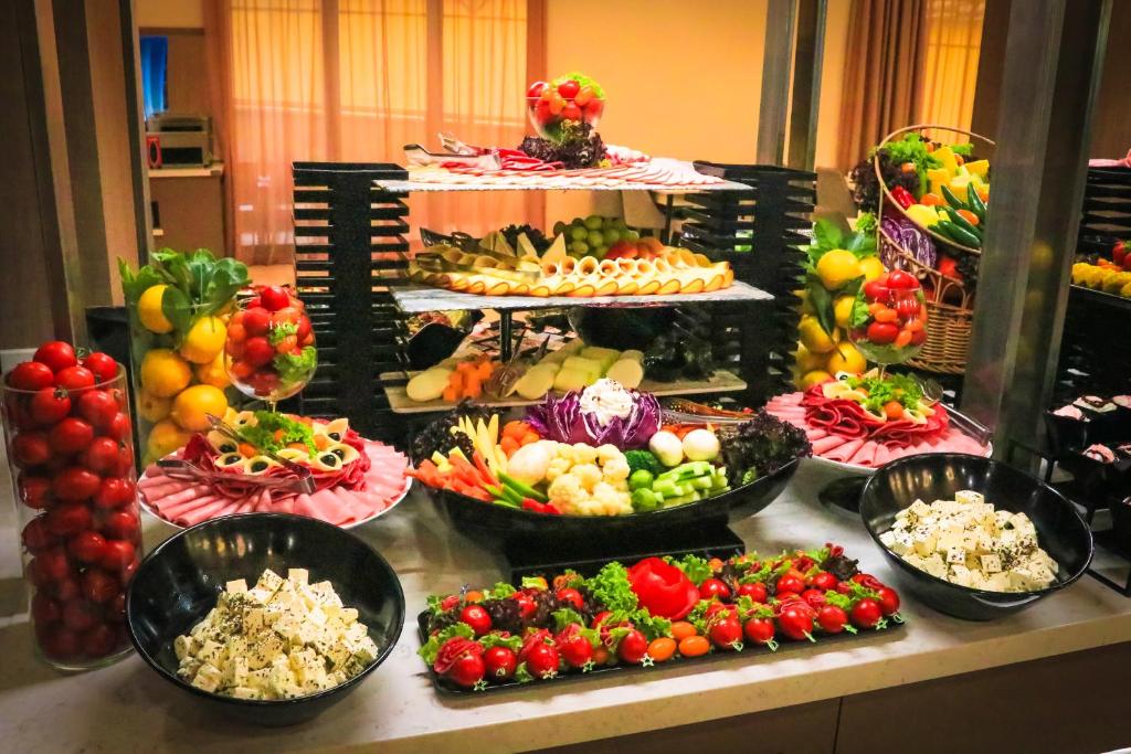 Svaigu dārzeņu un augļu bufete ar dažādām delikatesēm, ieskaitot sieru, gaļu un garnējumu, izkārtota vairākos līmeņos. Krāsaini dārzeņi un augļi veido pievilcīgu un garšīgu ēdienu izvēli.
