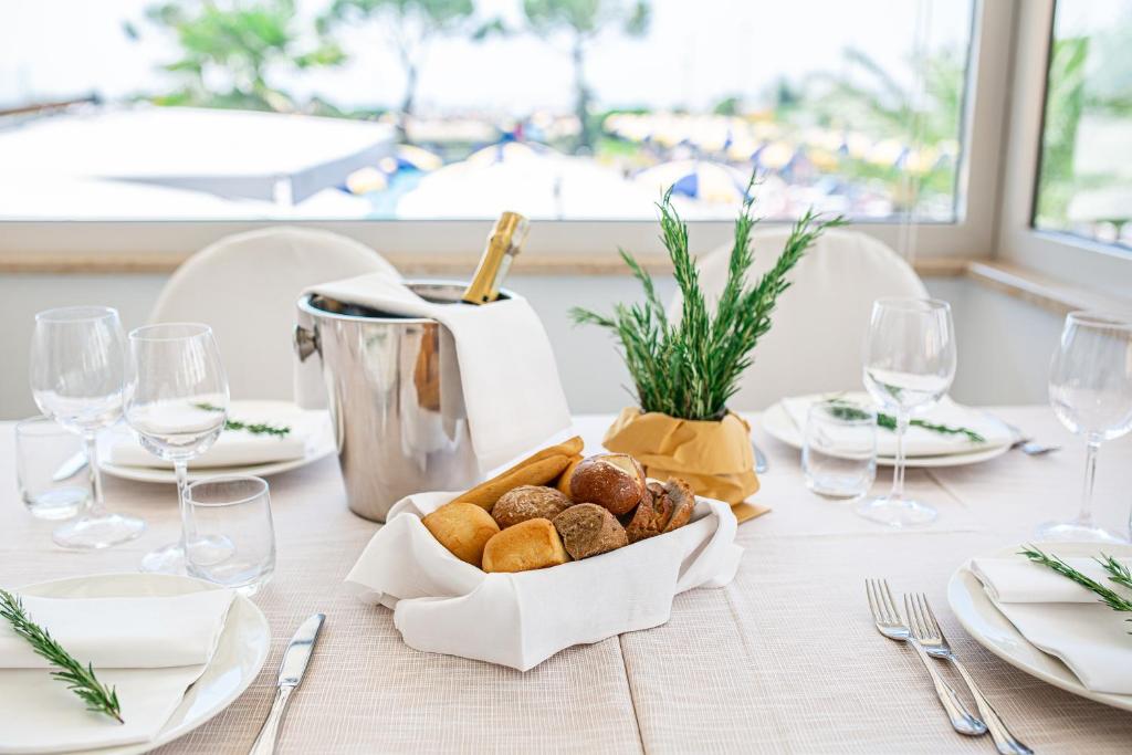 Elegants galda klājums ar maizi, dzērienu un zaļumiem, kas rada viesmīlīgu atmosfēru. Ideāli piemērots svinībām vai romantiskai maltītei.