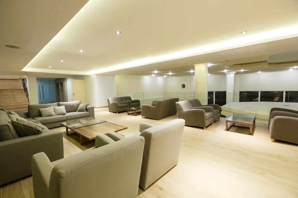 Mūsdienīga un plaša viesistaba ar ērtām pelēkām mēbelēm un koka galdu, kas nodrošina patīkamu un relaksējošu atmosfēru. Apgaismojums rada siltu noskaņu telpā.