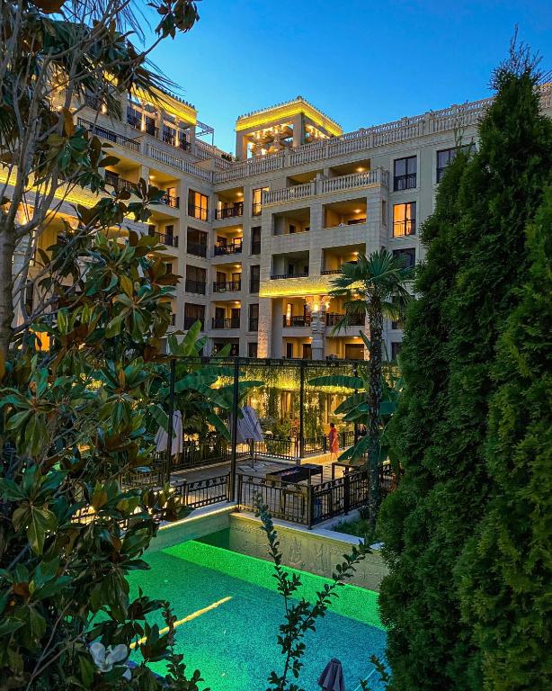 Elegants viesnīcas komplekss ar apgaismotām terasēm un zaļu baseinu, ko ieskauj tropiski augi un dārzi. Ideāla atmosfēra relaksācijai.