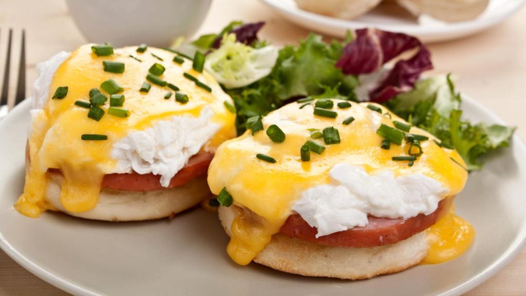 Olu omlete ar tomātu un šķiņķi, pārklāta ar sierīgu mērci, pasniegta kopā ar svaigiem salātiem.