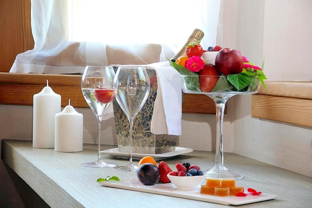 Eleganta galda kompozīcija ar glāzēm, augļiem un svečturiem, radot viesmīlīgu un relaksējošu atmosfēru. Izsmalcinātība un svaigums apvienoti vienā attēlā.