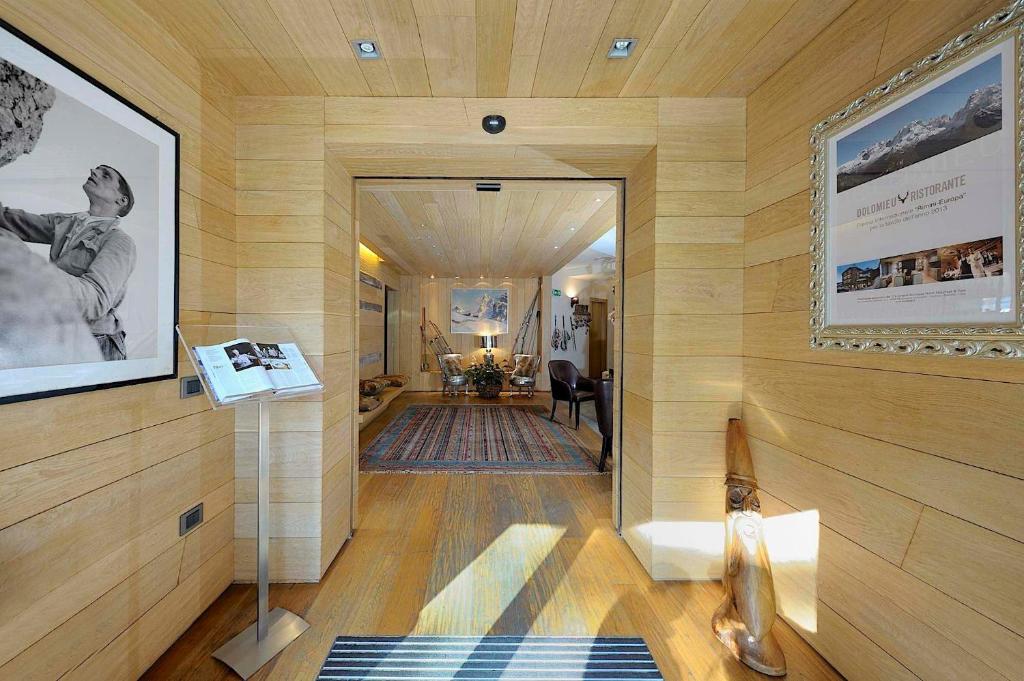 Mūsdienīga un eleganta ieejas zona ar koka apdari, melnbaltu fotogrāfiju pie sienas un dizaina elementiem, kas veido siltu atmosfēru. Ieejas telpā redzami arī dekoratīvi elementi un mēbeles, kas piešķir telpai raksturu.