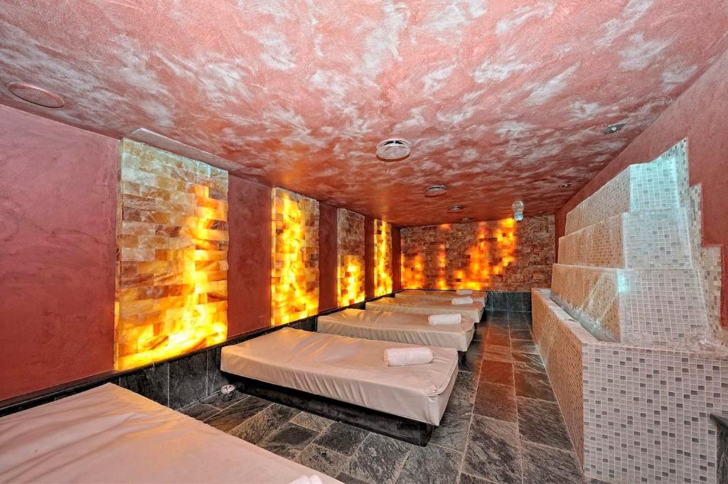 Relaksējoša spa telpa ar gultām un siltām gaismas sienām, kas radījušas mierīgu atmosfēru. Interjers apvieno dabīgus akmeņus un modernus elementus.