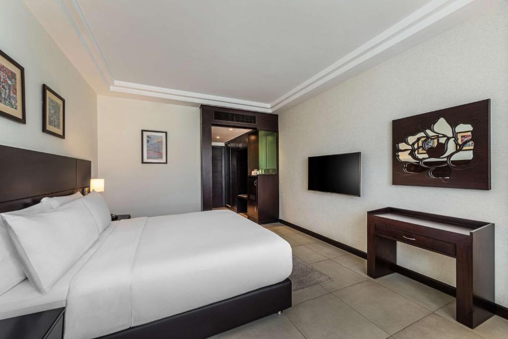 Mūsdienīga viesnīcas istaba ar ērtu gultu, televizoru un elegantu interjeru, kas ietver mākslas darbus uz sienām. Istaba ir gaiša un plaša, nodrošinot patīkamu atmosfēru.