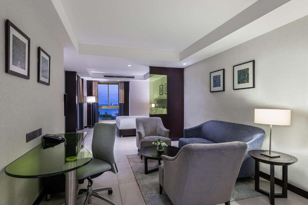 Mūsdienīga viesnīcas istaba ar ērtām mēbelēm, galdu un skatu uz jūru. Gaisma un eleganta interjera dizains rada patīkamu atmosfēru.