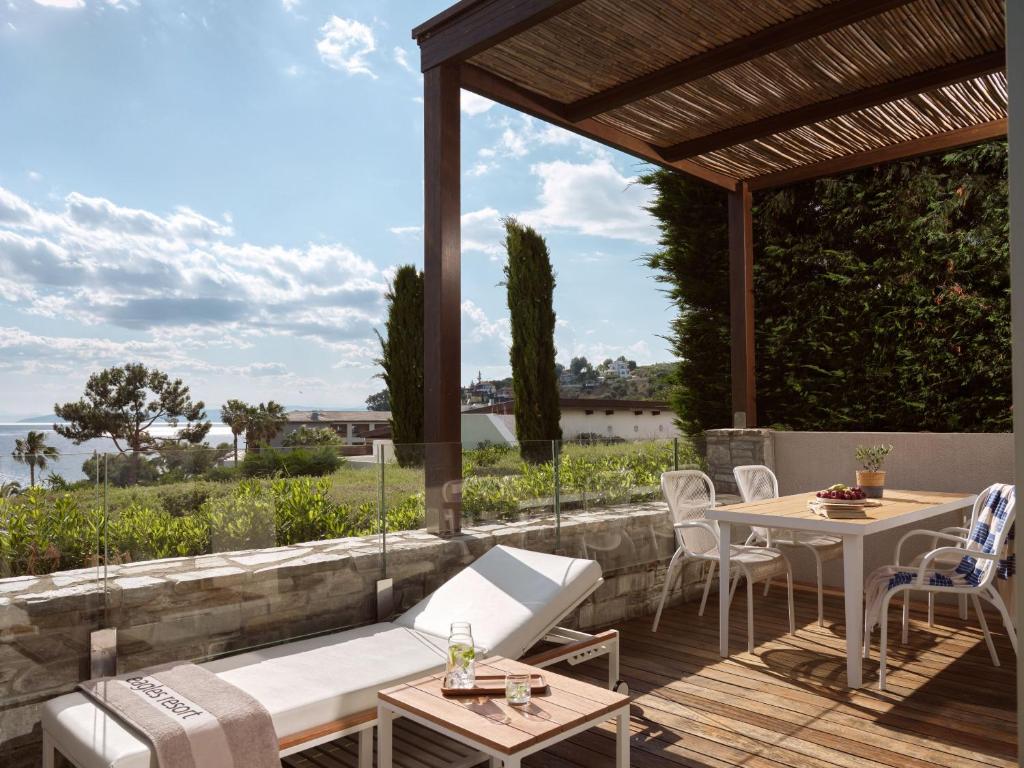 Mūsdienīgs terases dizains ar atpūtas krēslu un galdu, skats uz dārzu un jūru. Ideāla vieta relaksācijai un baudīšanai ārpus telpām.