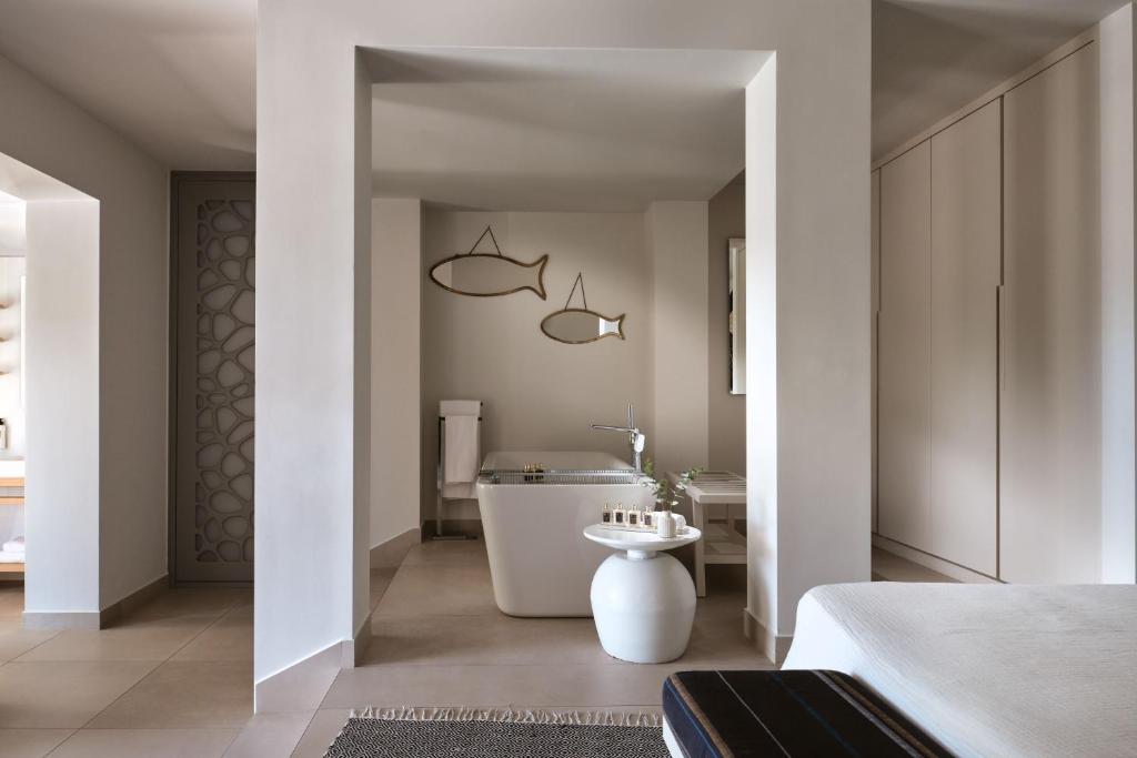 Mūsdienīgs vannas istabas interjers ar elegantām līnijām, kas ietver vannu, dekora elementus un gaišas krāsas. Vieta izstaro mierīgu atmosfēru un stilīgu estētiku.