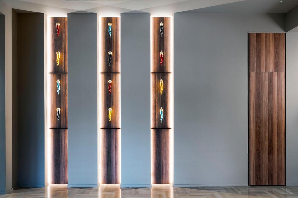 Sienas dizains ar dekoratīviem gaismas elementi, kas izceļ krāsainas figūras uz koka fona. Moderns interjers ar elegantu apgaismojumu un estētisku kompozīciju.