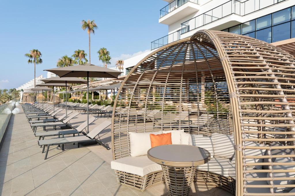 Lieliska atpūtas zona ar vīnogulāju stila nojumi, ērtām mēbelēm un saules krēslām, kas atrodas pie modernas viesnīcas. Ideāla vieta relaksācijai, baudot sauli un dabu.