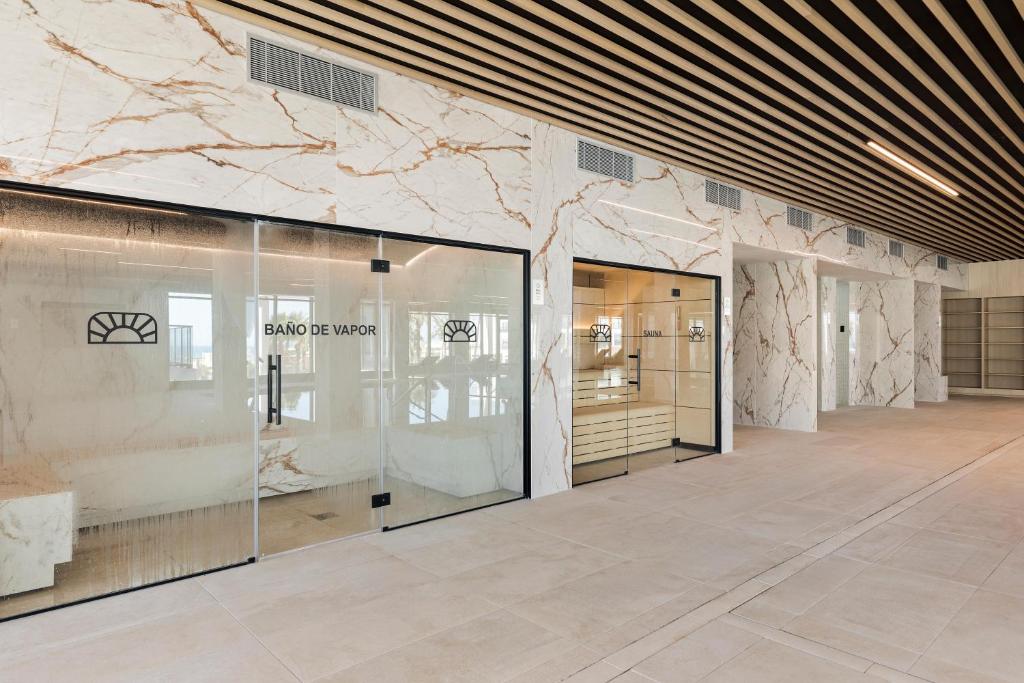 Mūsdienīgs spa interjers ar marmora apdari un stikla durvīm, kas ved uz tvaika pirts un saunu. Stilu papildina koka griesti un minimālisma dizains.