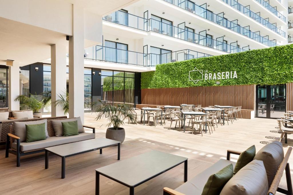 Mūsdienīgs terases restorāns ar zaļu vertikālo dārzu un modernām mēbelēm, kas piedāvā ērtu atpūtu ārā. Ideāla vieta relaksācijai un socializēšanai.