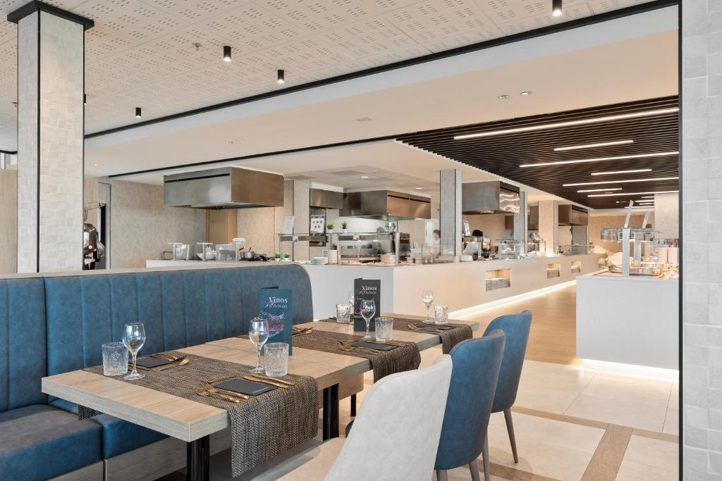 Mūsdienīgs restorāns ar elegantu interjeru, kurā redzami ēdamgaldi ar zilu apdari un akcentiem, kā arī atvērta virtuve. Gaismas elementi piešķir siltu atmosfēru.