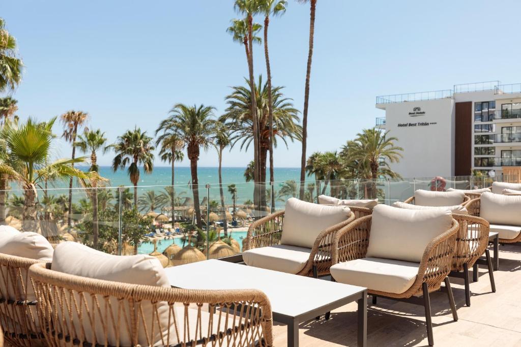 Sauļota terase ar modernām mēbelēm un skatu uz jūru, ko ieskauj palmas un viesnīca. Ideāla vieta atpūtai un relaksācijai.