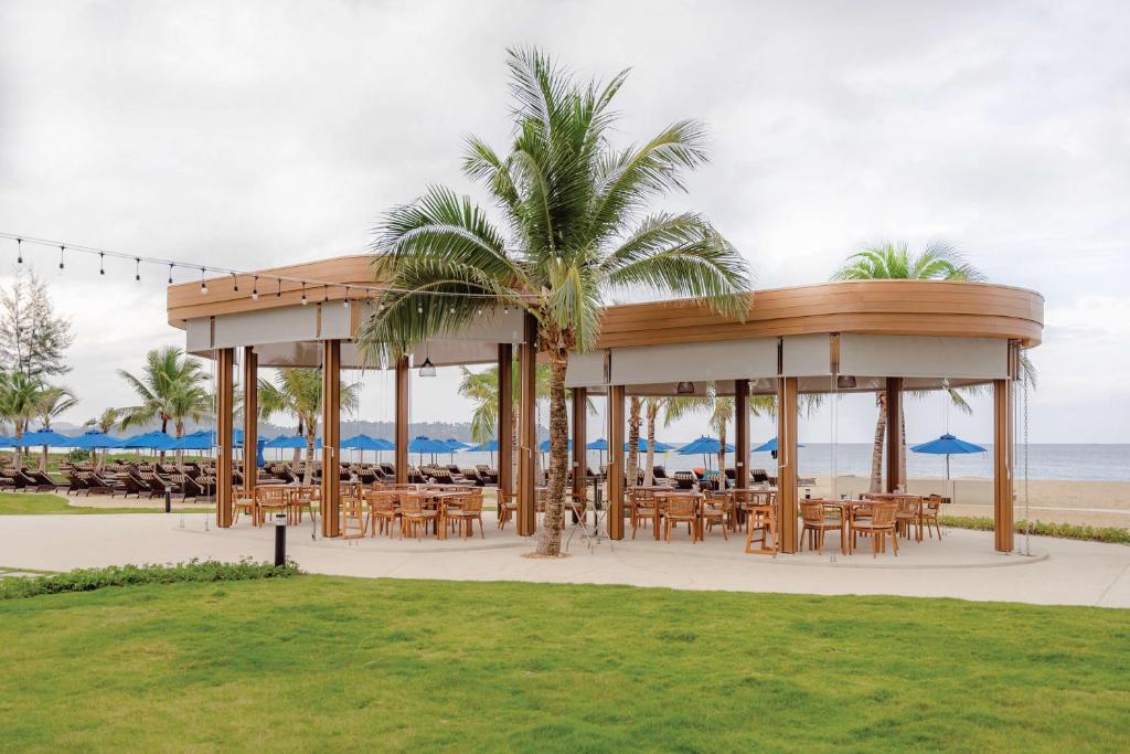 Atpūtas zona piekrastē Angsana Laguna Phuket ar koka konstrukciju un galdiem.