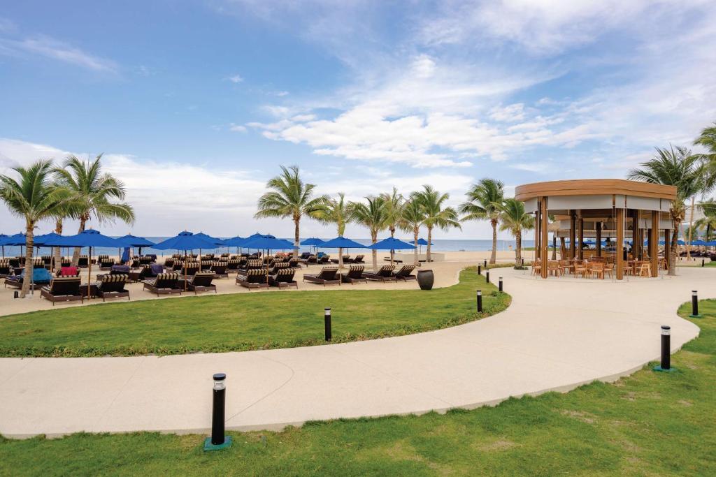 Viesnīca Angsana Laguna Phuket piekrastē ar sauļošanās krēsliem un palmu kokiem.