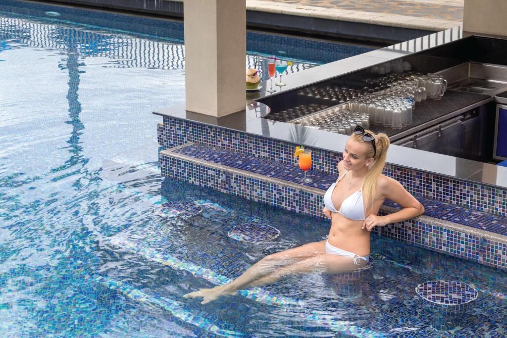 Sieviete atpūšas pie baseina Angsana Laguna Phuket, baudot kokteili.