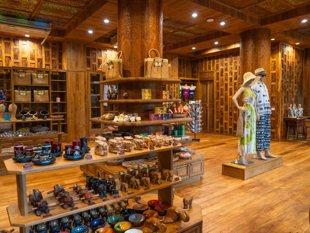 Koka amatniecības veikals ar dažādiem suvenīriem, rotājumiem un apģērbiem, kas izkārtoti uz plauktiem. Veikalā ir siltas gaismas un dabīgā koka interjers.