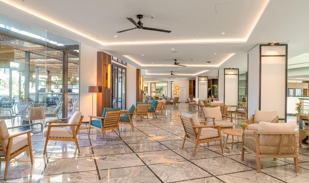 Moderns viesnīcas vestibils ar elegantiem krēsliem un marmora grīdu, kas nodrošina komfortablu un stilīgu atmosfēru. Plašas logu daļas ļauj ieplūst dabiskajai gaismai.