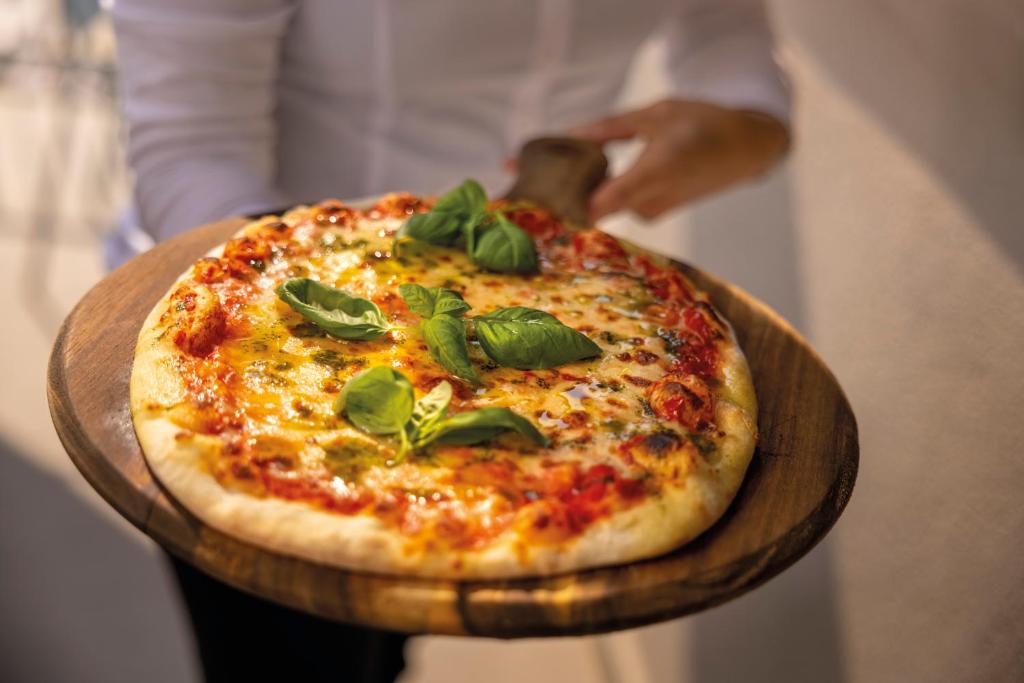 Svaiga, cepta pica ar tomātiem un baziliku, pasniegta uz koka dēļa. Ideāla izvēle itāļu virtuves mīļotājiem.