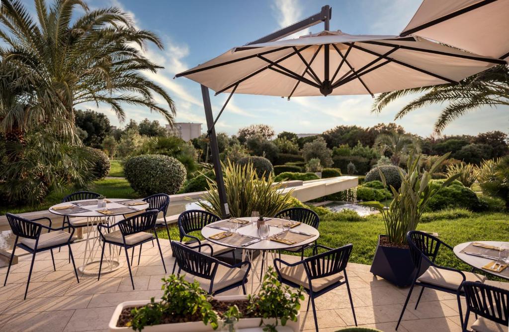 Elegantā restorāna terase ar modernām mēbelēm, plašiem saules lietussargiem un zaļojošiem dārziem apkārt. Ideāla vieta relaksācijai un ēdienošanai brīvā dabā.